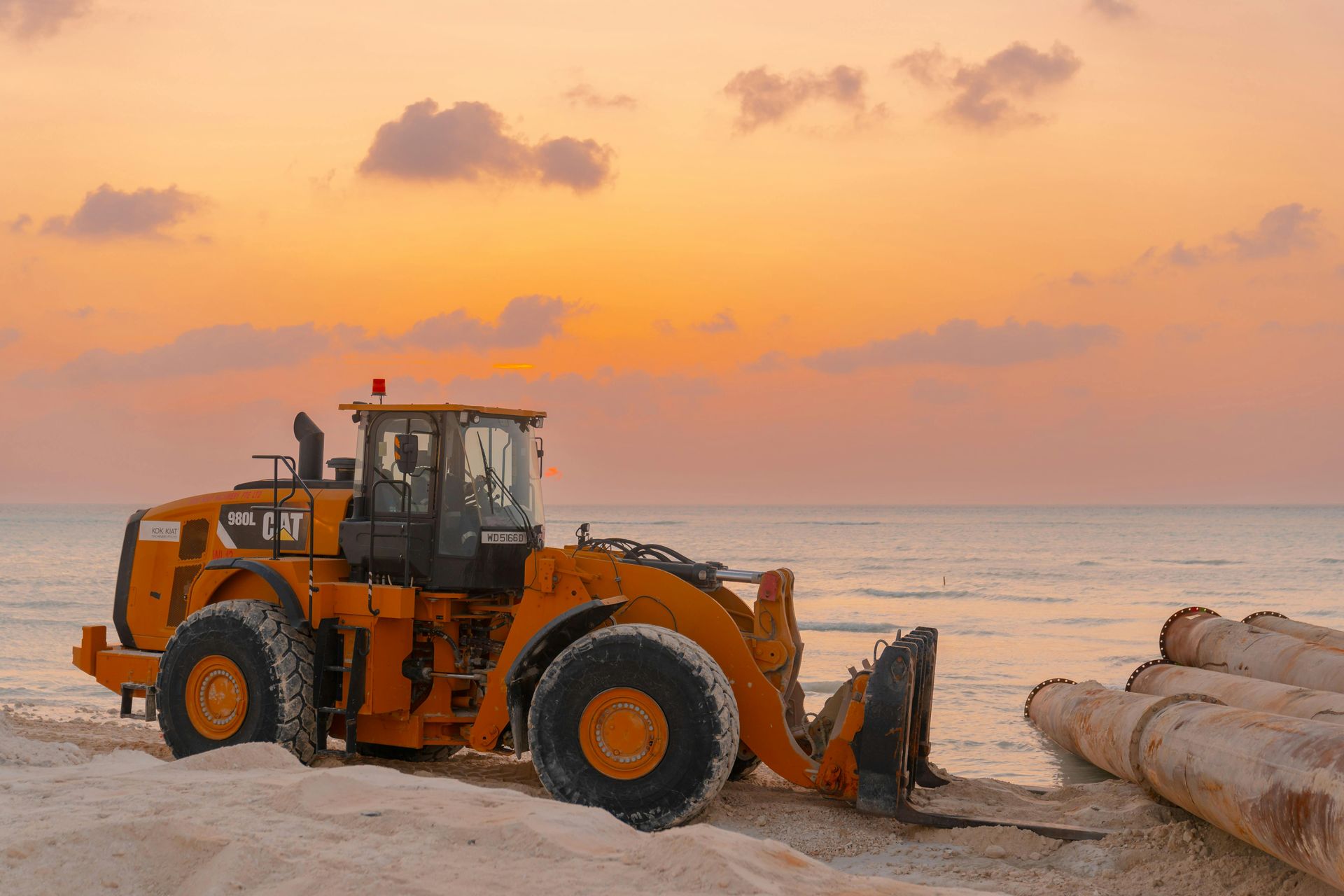 excavation equipment on the beach picking up pipes