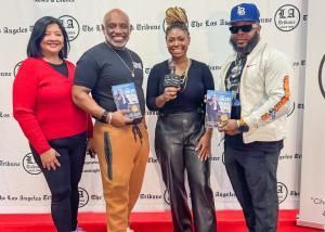 Four people posing with books at a red-carpet event in front of a step-and-repeat backdrop