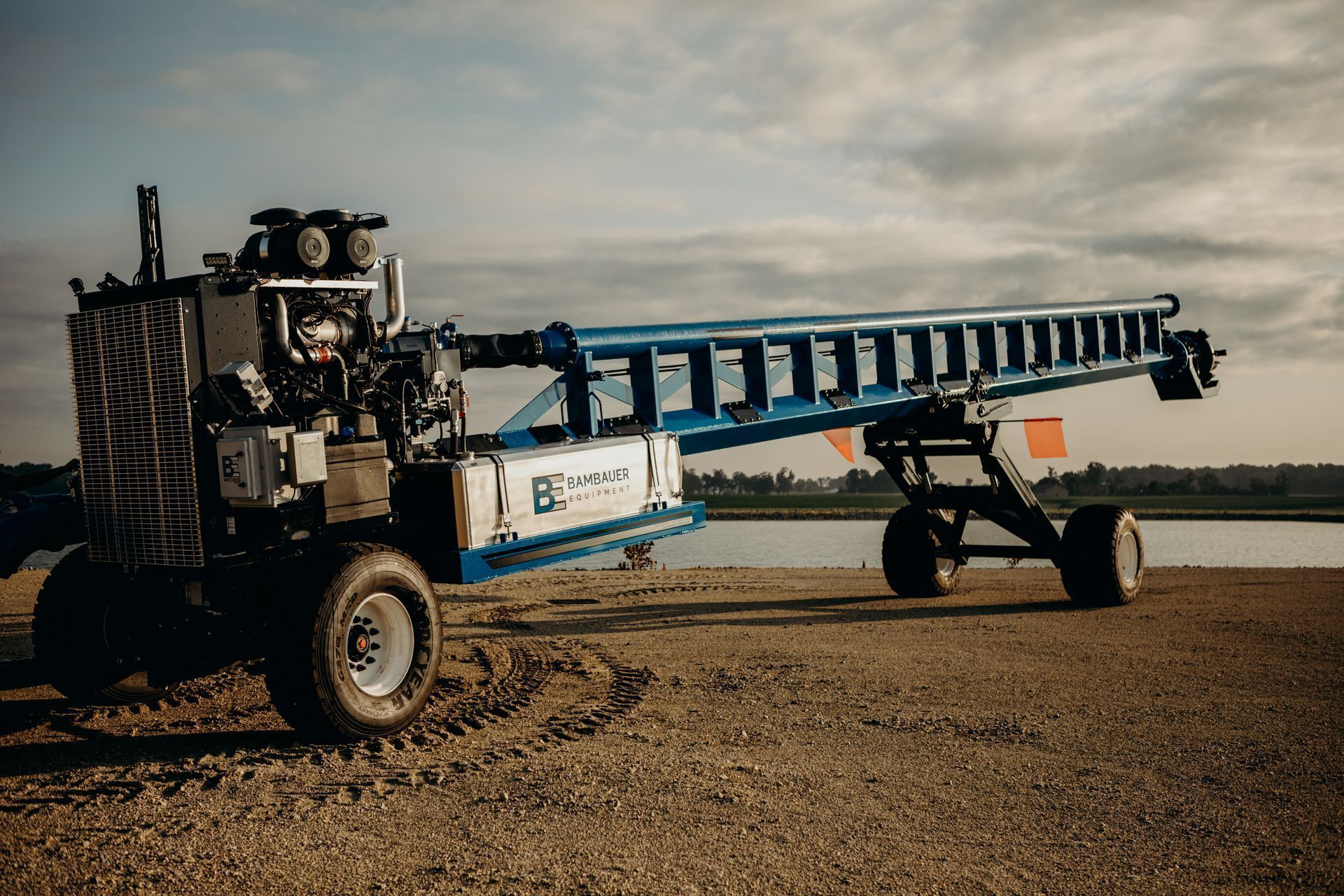 Long blue agricultural sprayer in a field under a cloudy sky