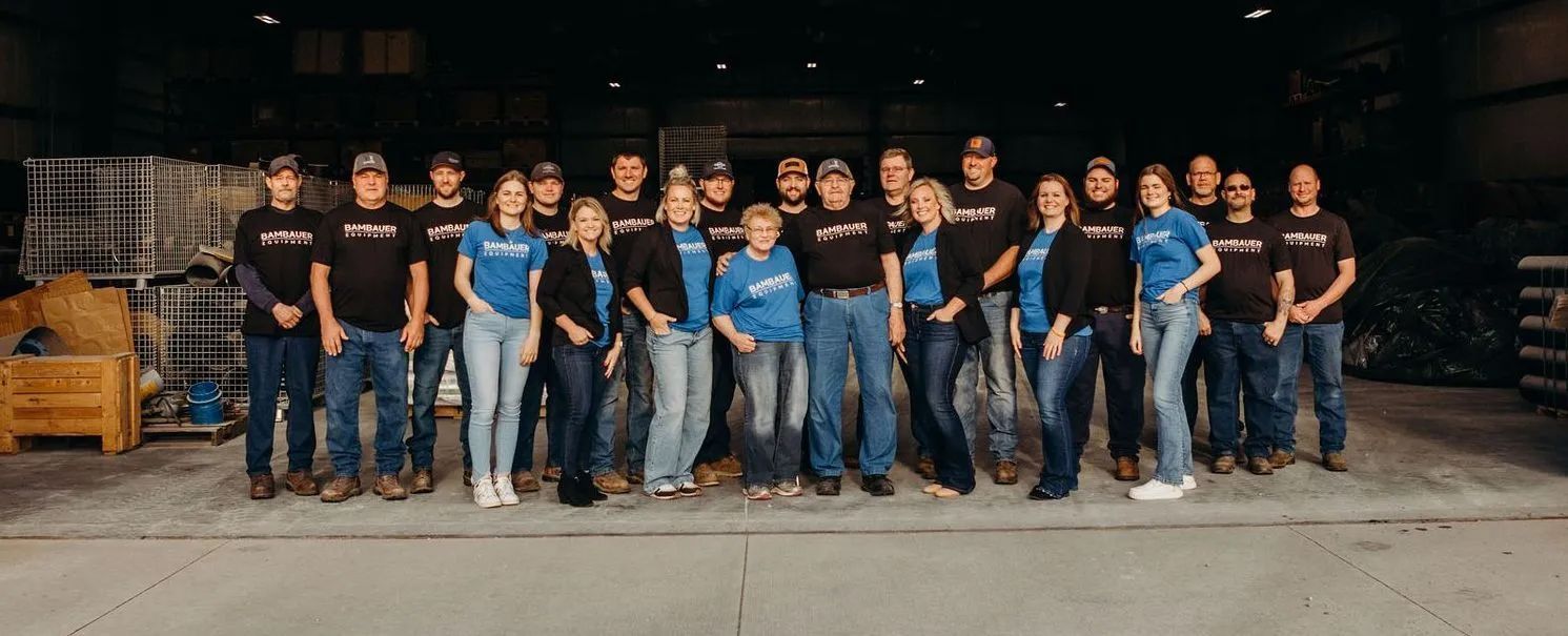Group of people standing together in a dim warehouse, wearing black and blue shirts and jeans