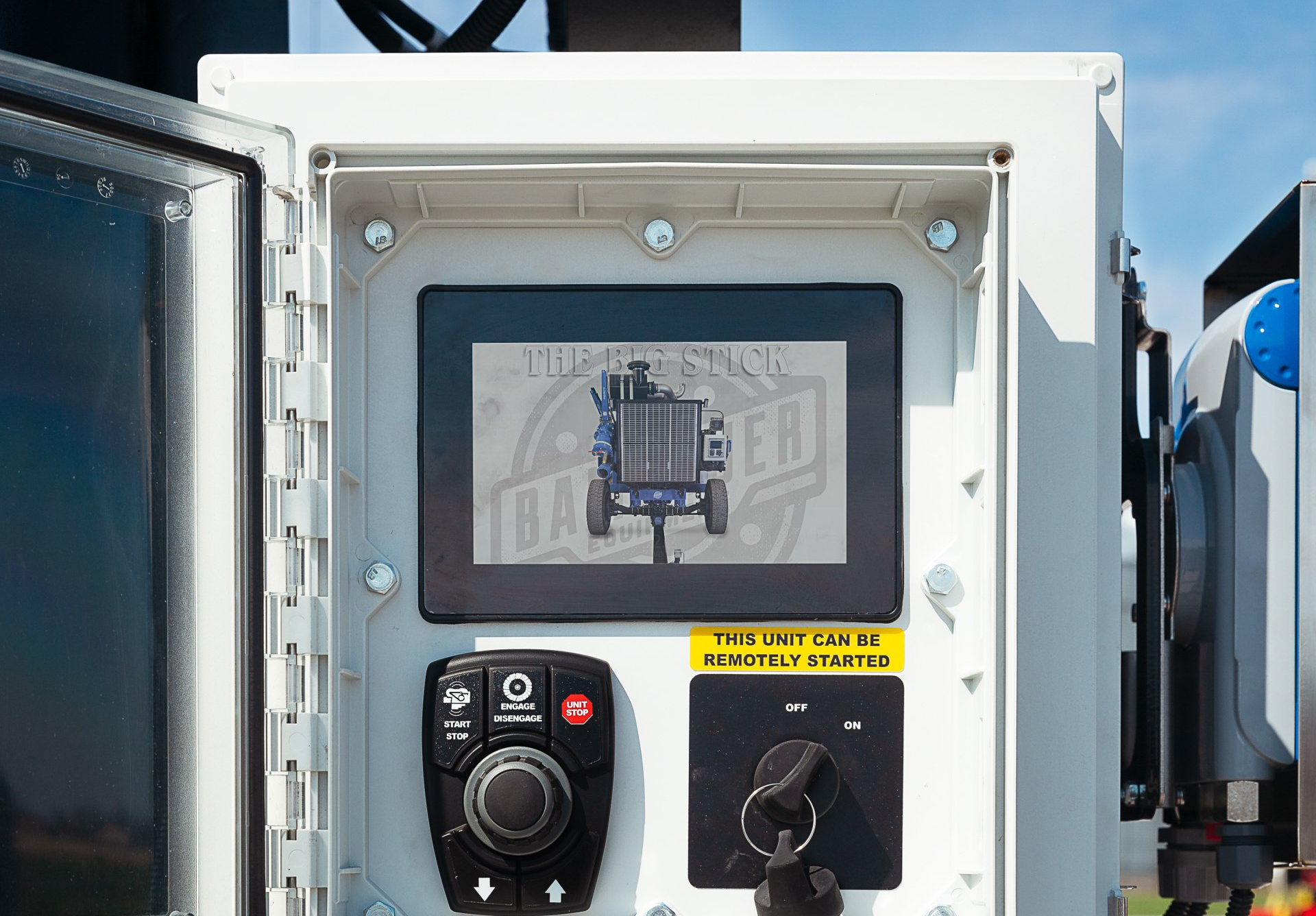 Industrial control panel with a small display, black knobs, and yellow safety labels inside a white cabinet