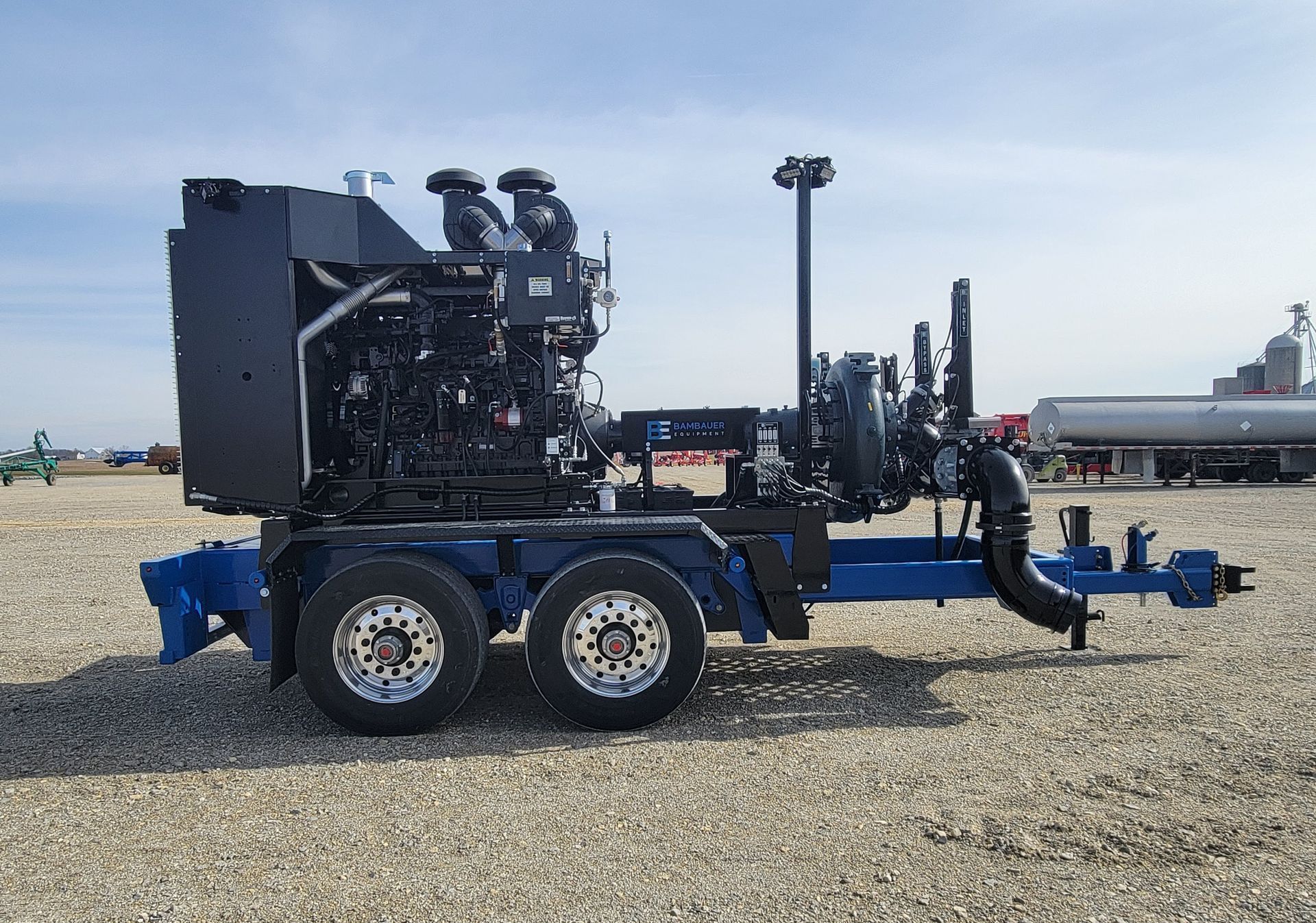 Blue industrial trailer-mounted engine on gravel lot under clear sky.