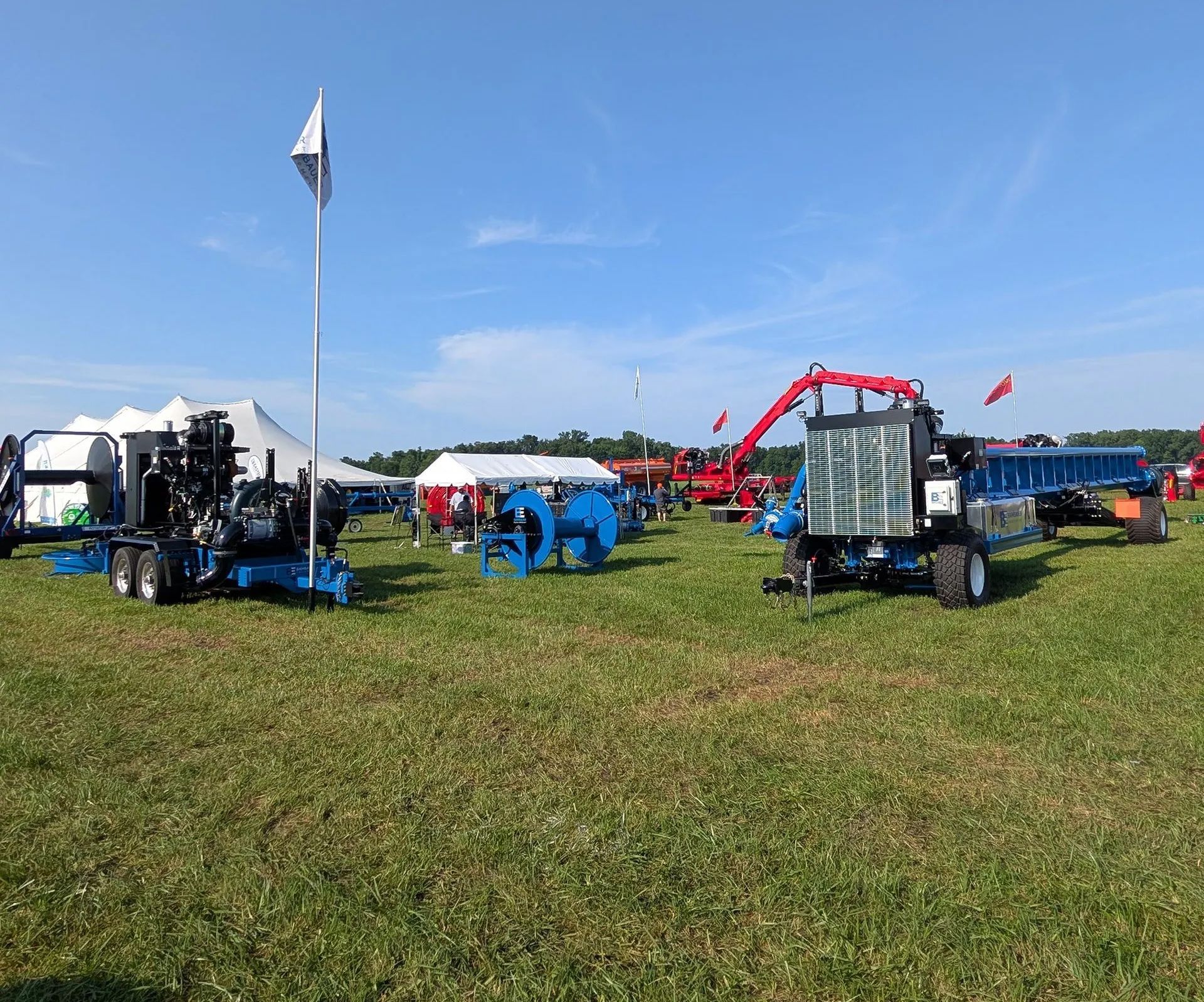 Blue farm machinery on a grassy field at an outdoor event under a clear sky