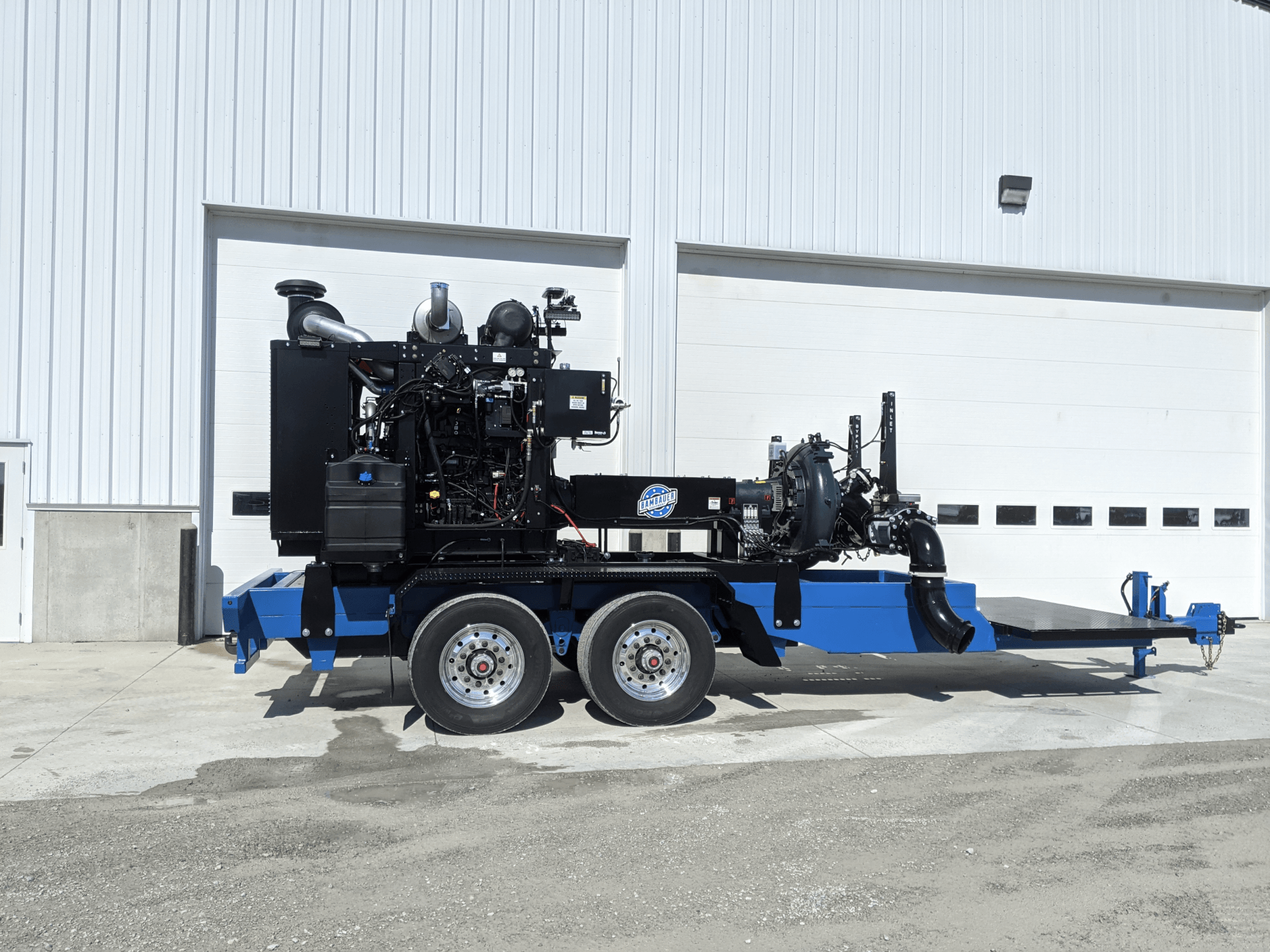 Blue industrial trailer-mounted machinery parked outside a white building.