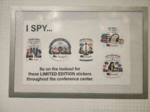 I SPY poster with limited edition stickers displayed in a conference center hallway.