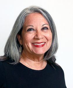 Smiling woman with gray hair in a black top against a white background