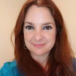 Portrait of a smiling woman with auburn hair against a light background