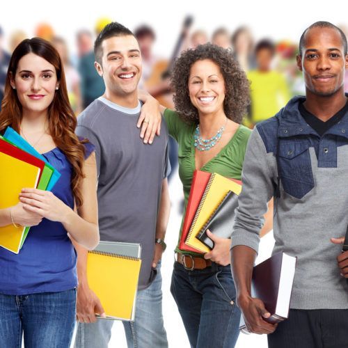 Group of smiling students holding colorful notebooks against a blurred classroom-style background
