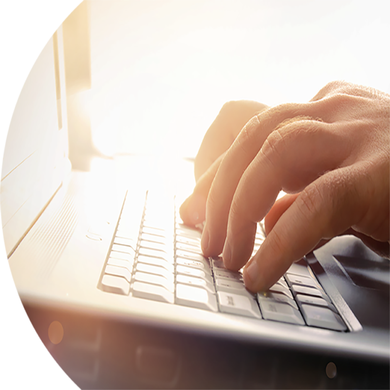 Hands typing on a laptop keyboard in bright sunlight