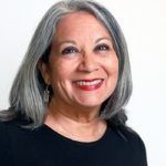 Smiling woman with gray hair in a black top against a light background