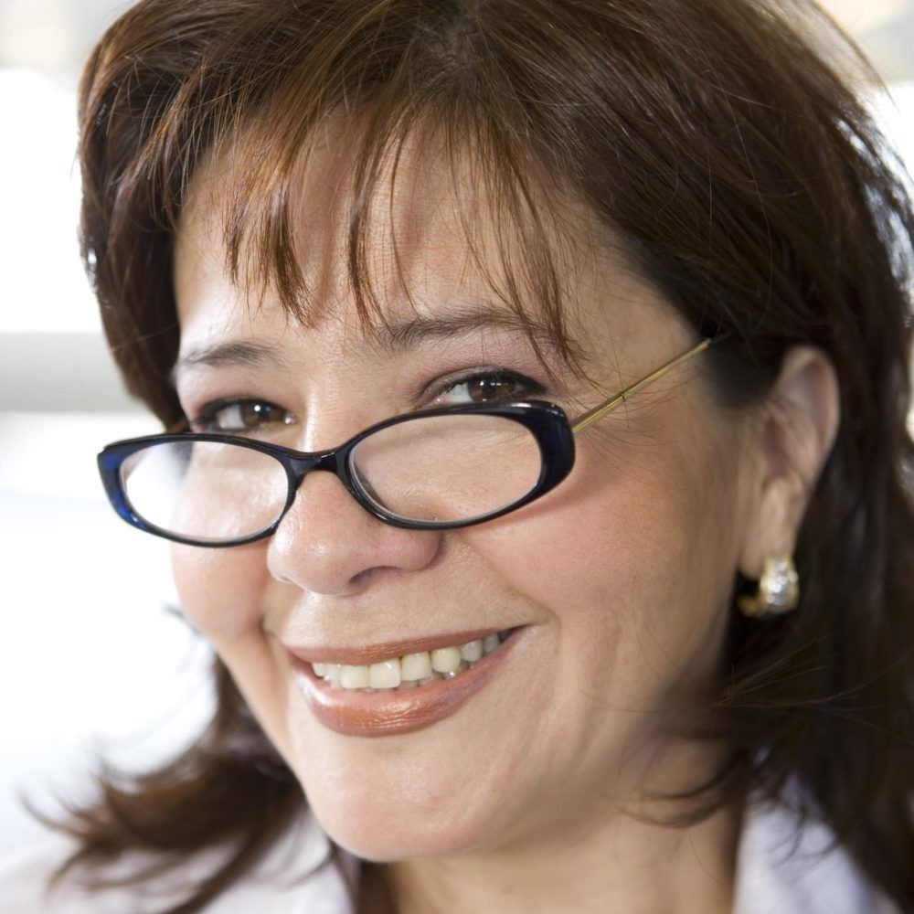 Smiling person wearing glasses, close-up portrait against a bright background