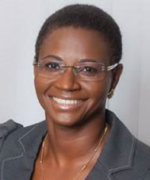 Smiling person wearing glasses and a dark blazer against a gray background
