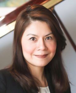 Portrait of a woman smiling, with straight dark hair, wearing a dark blazer.