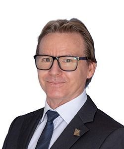Portrait of a man in glasses and a dark suit against a white background
