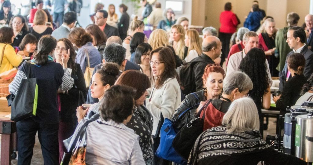 Crowded airport check-in line with travelers standing with luggage and talking
