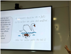 Projected classroom slide with a swan drawing and handwritten notes beside a small text box.