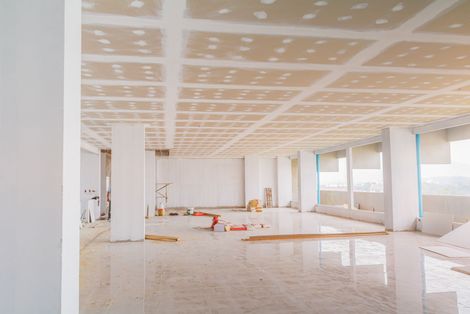 Intérieur de bureau vide et inachevé avec des colonnes blanches, un sol carrelé et des matériaux de construction éparpillés autour