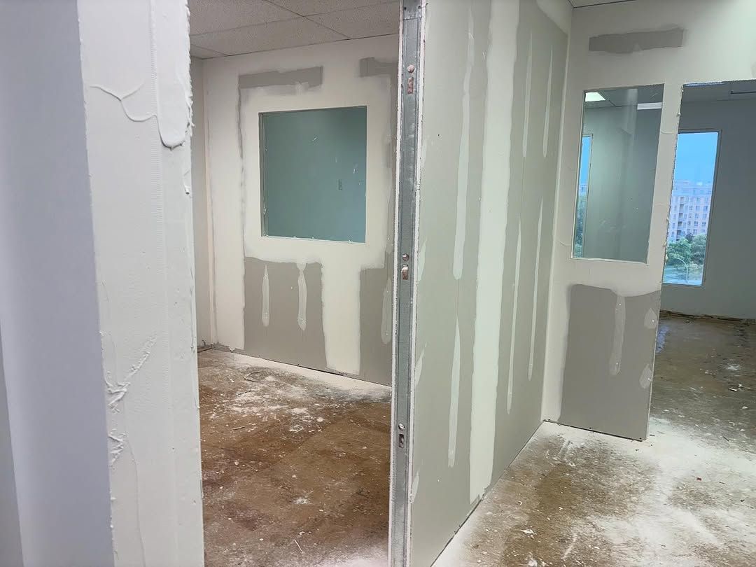 Intérieur inachevé avec cloisons sèches, portes ouvertes et poussière blanche au sol