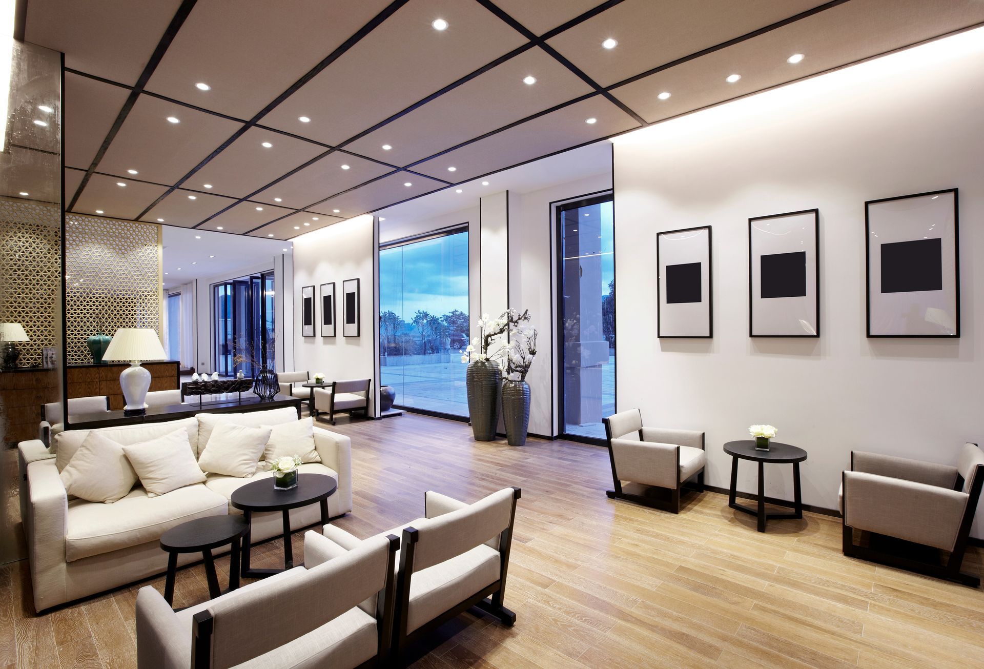 Modern hotel lounge with beige seating, framed wall art, and warm wood flooring