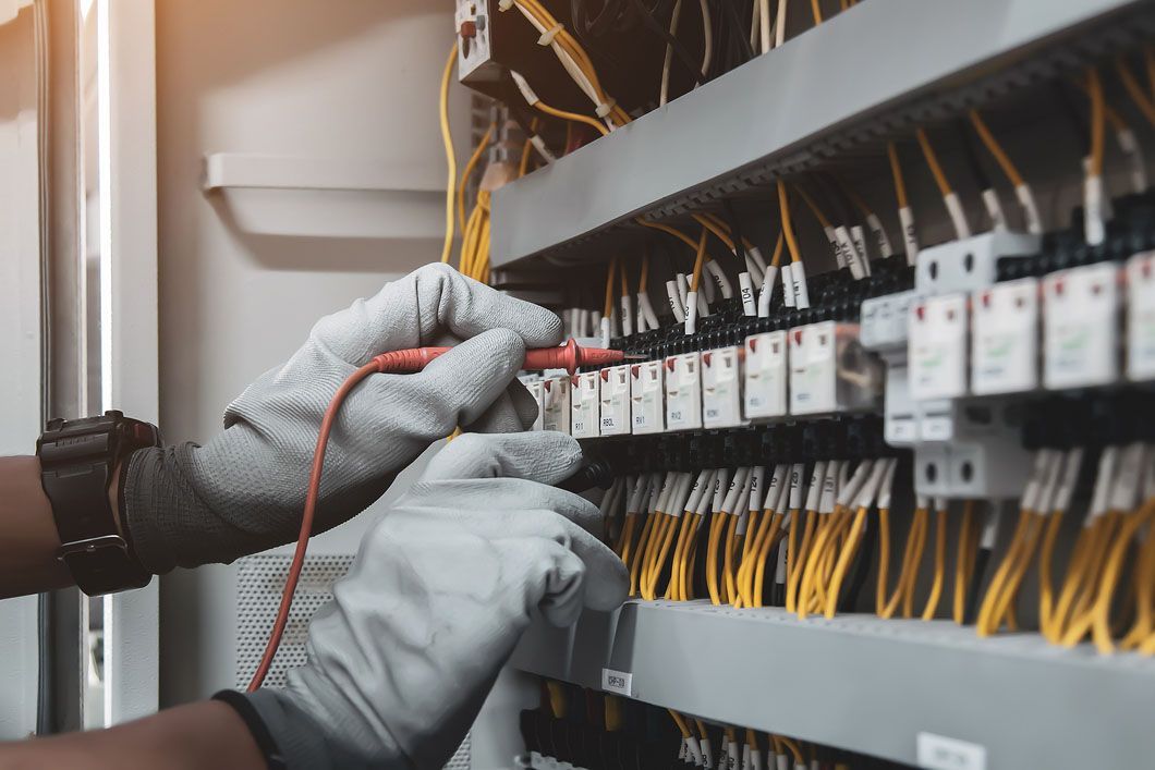 An electrician is working on an electrical panel in a control room.