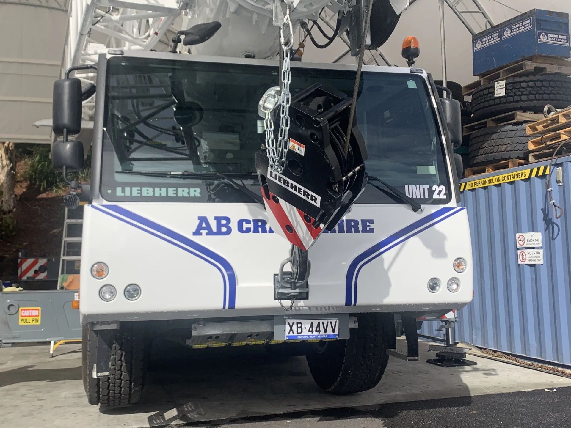 White Liebherr crane truck with blue stripes parked at a construction site.