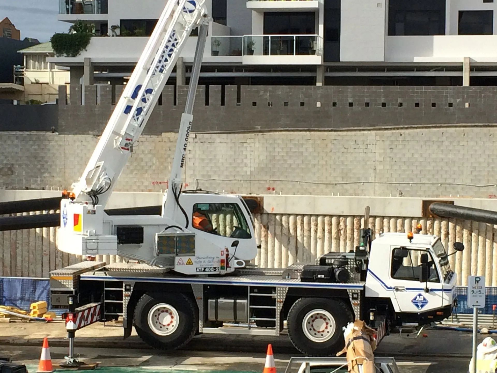 White crane truck parked beside a waterfront construction site with a concrete retaining wall