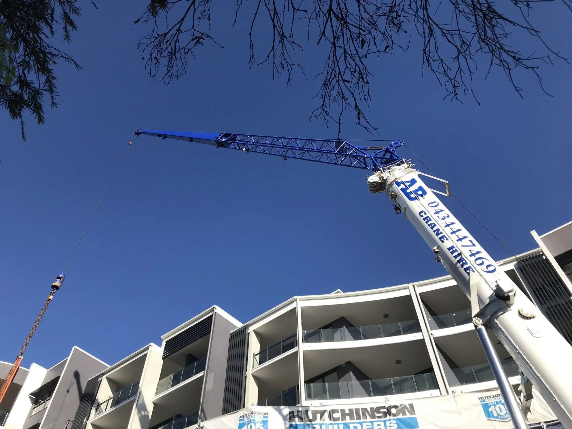 Construction crane beside a white building under a clear blue sky