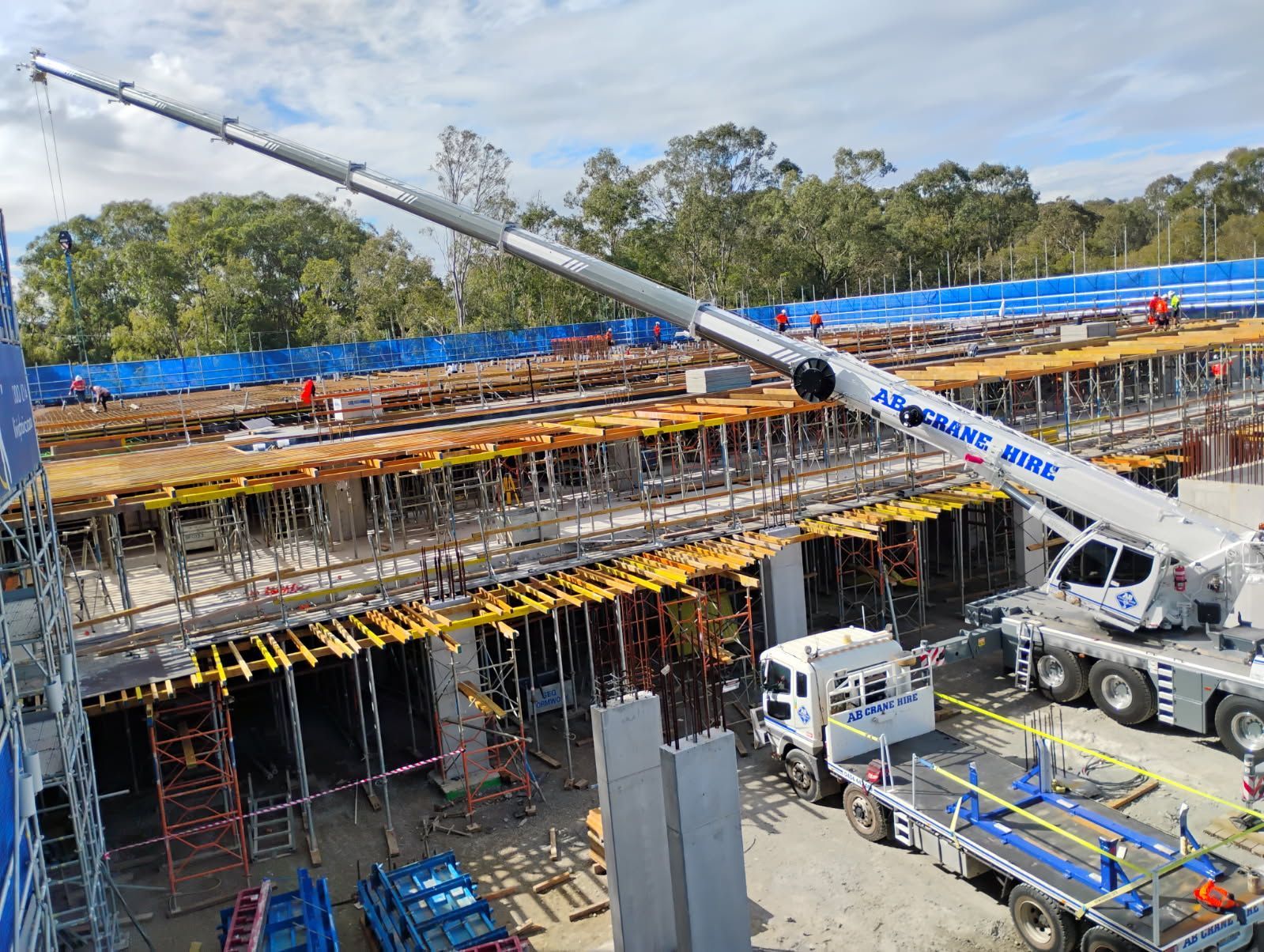 Construction site with a large crane lifting materials over a partially built structure under blue sky