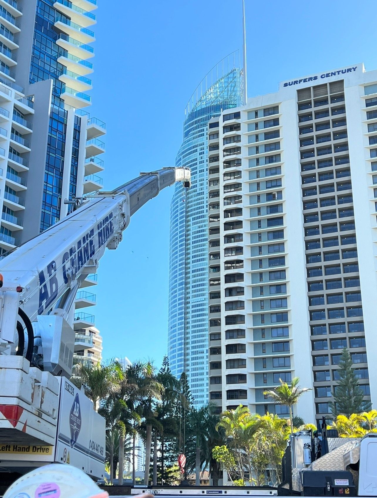 Construction crane reaching toward high-rise buildings in a sunny urban area