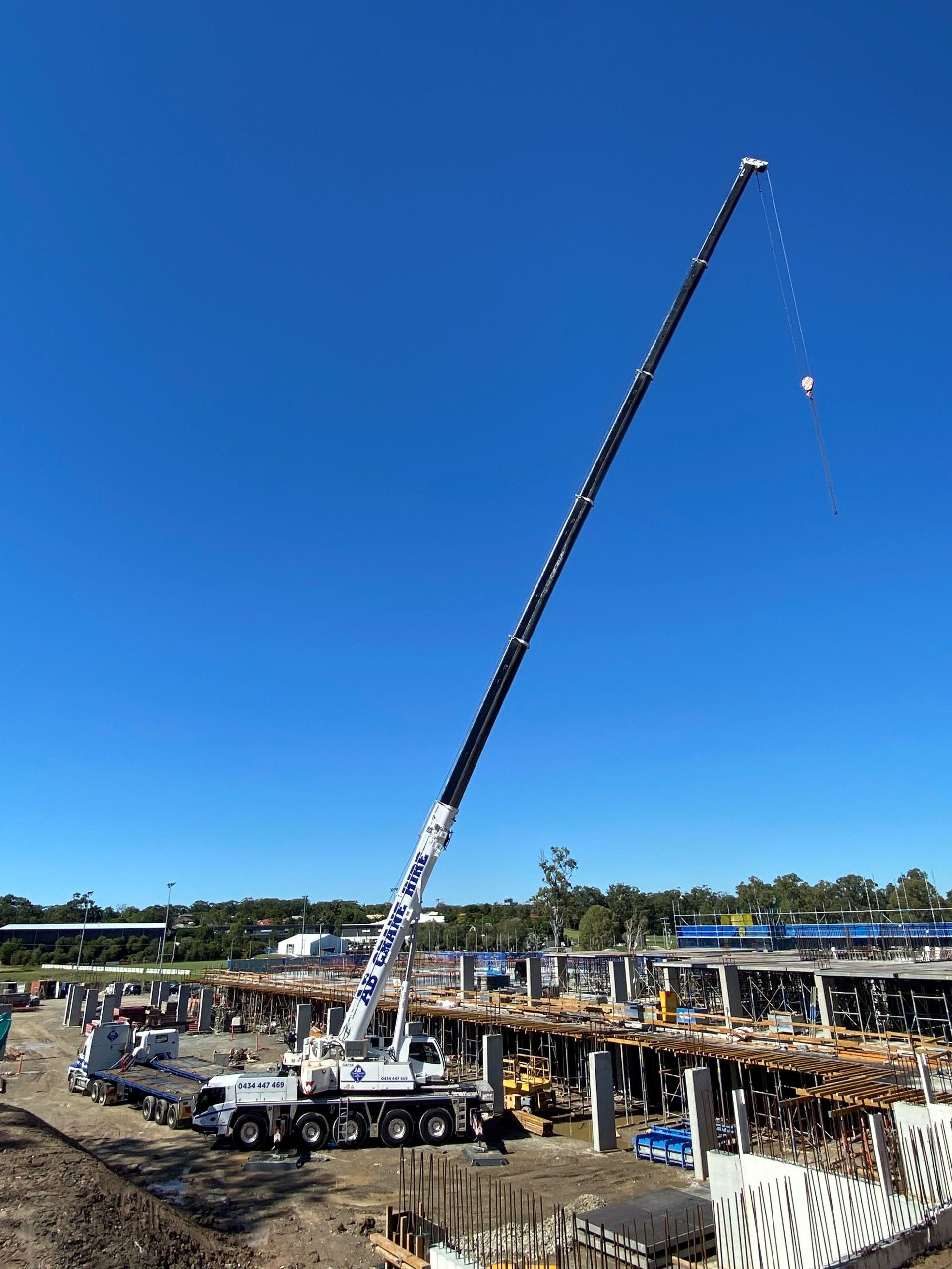 Tall crane lifting materials at a construction site under a clear blue sky