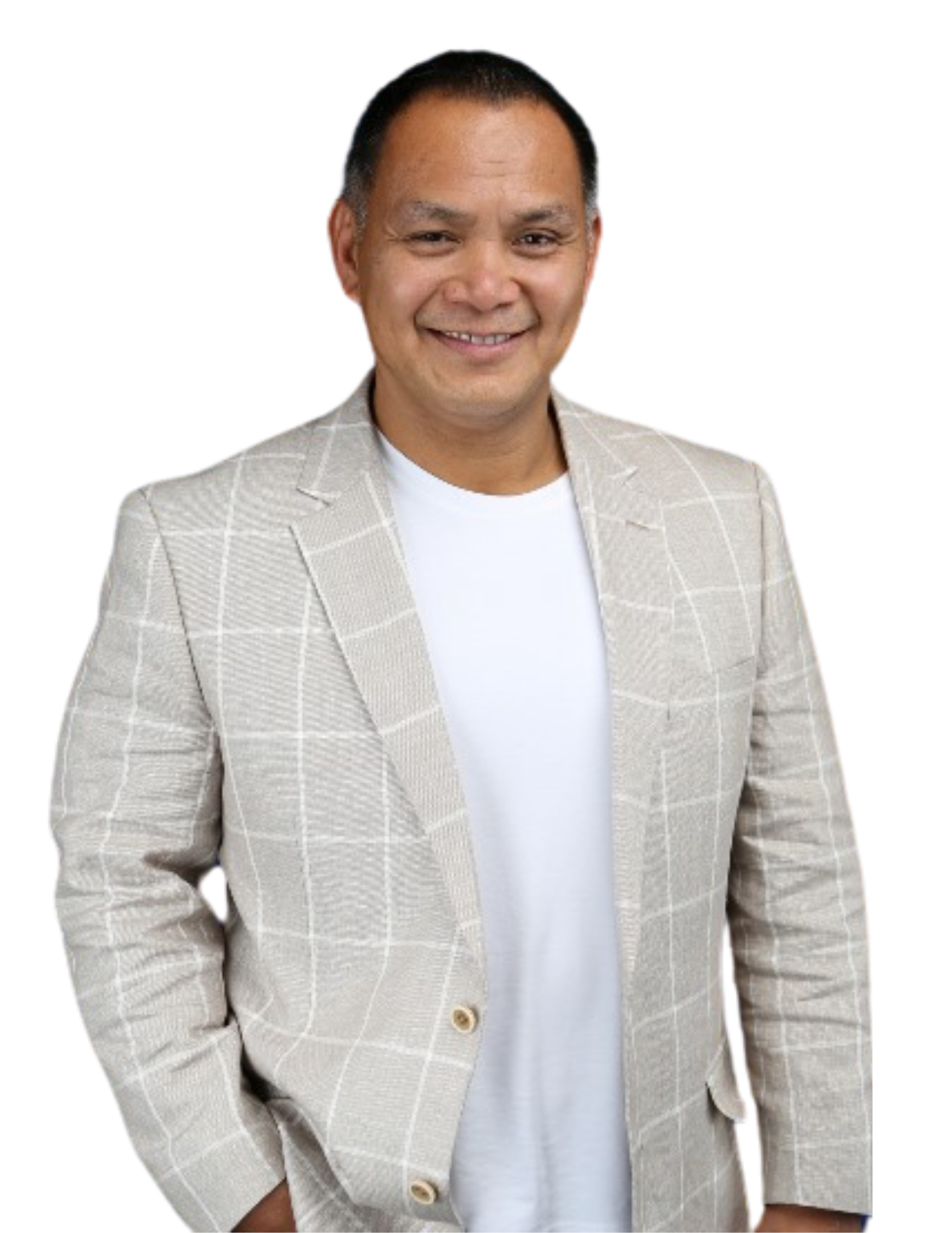 A man wearing a plaid jacket and a white shirt is standing with his hands in his pockets.
