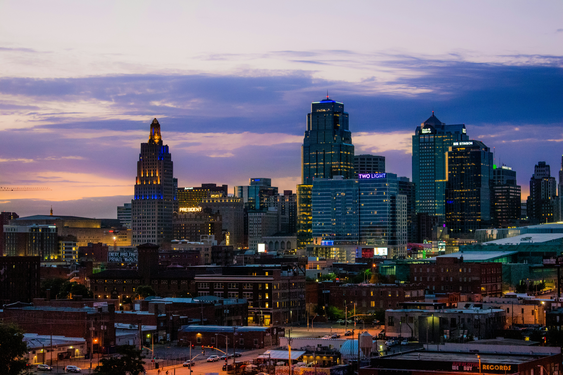City skyline at dusk with illuminated skyscrapers under a purple-blue sunset sky