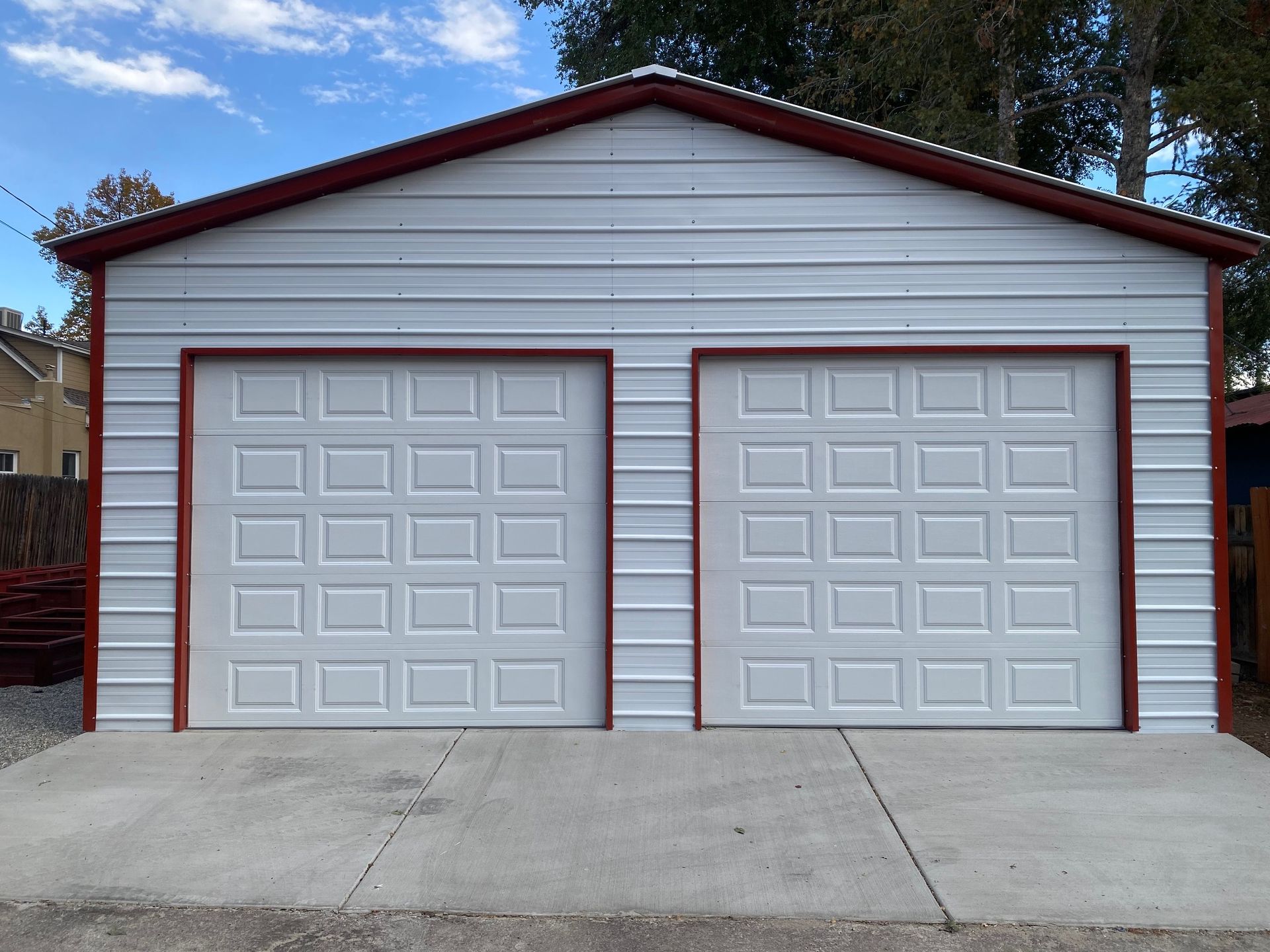 White metal two-car garage with red trim, two doors, and concrete driveway.