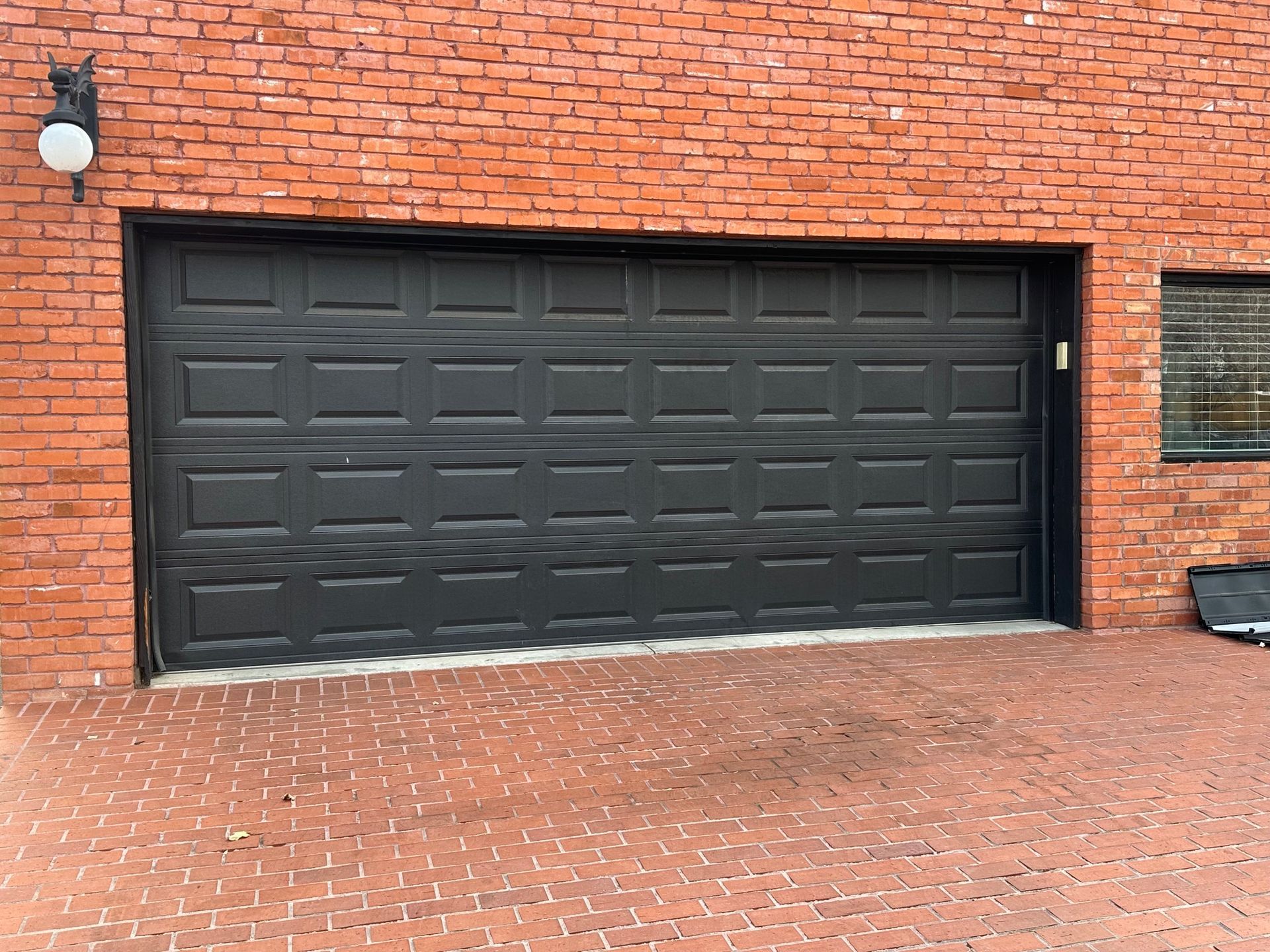 Black garage door in a brick building.