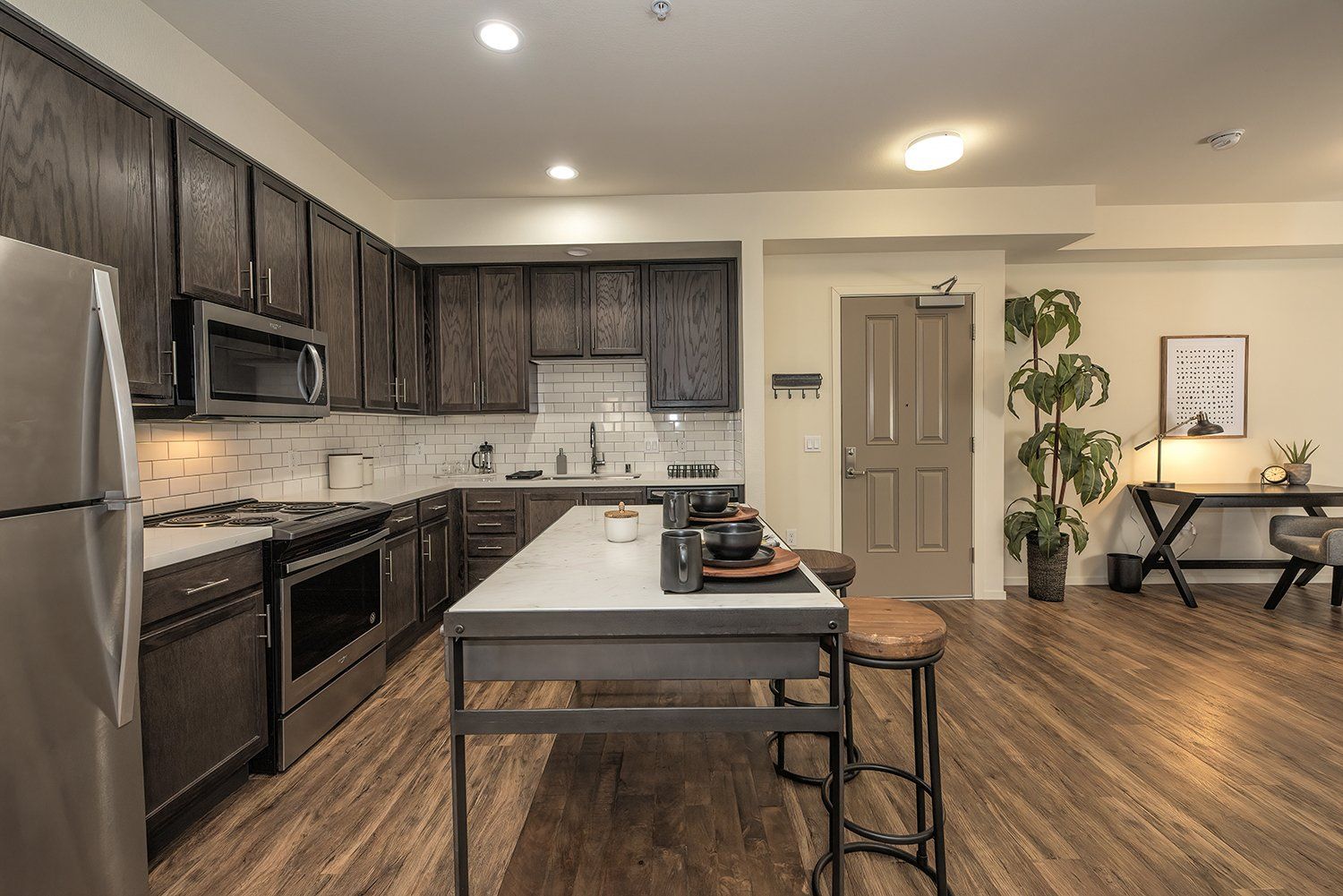 Luxury Apartments for Rent in El Cerrito, CA - Metro 510 - Kitchen with Hardwood-Style Flooring, Dark Wood Cabinets, Stainless Steel Appliances, and Moveable Island with Barstools.