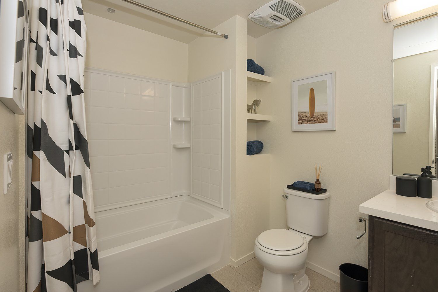 Two BR Apartments in El Cerrito, CA - Metro 510 - An interior shot of the bathroom featuring a tub/shower combo, large mirrors, and built-in shelves