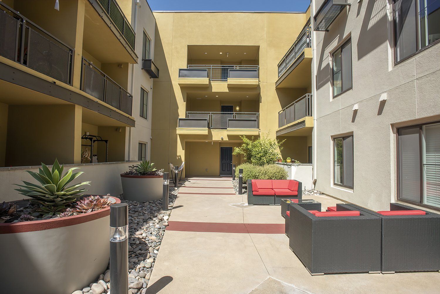 El Cerrito Apartments - Metro 510 - Courtyard In The Heart Of The Complex. The Courtyard Has Plush Seating, Stools, Lights, Potted Plants, And Maintained Landscaping.