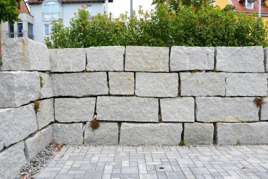 A Stone Wall With A Brick Walkway In Front Of It — Tony Eldridge Property Services in Forster, NSW
