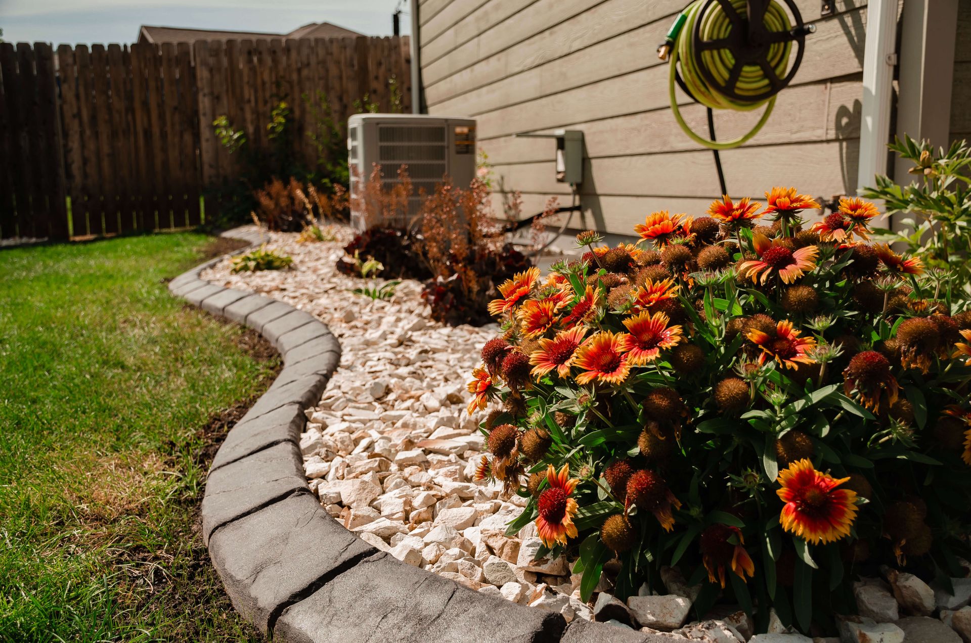 A garden with flowers and rocks in front of a house.