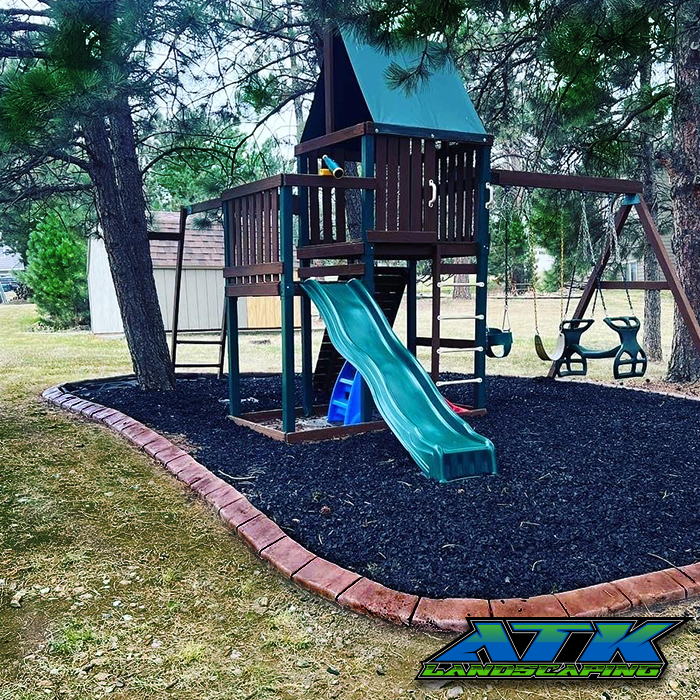 A playground with a slide and swings surrounded by trees