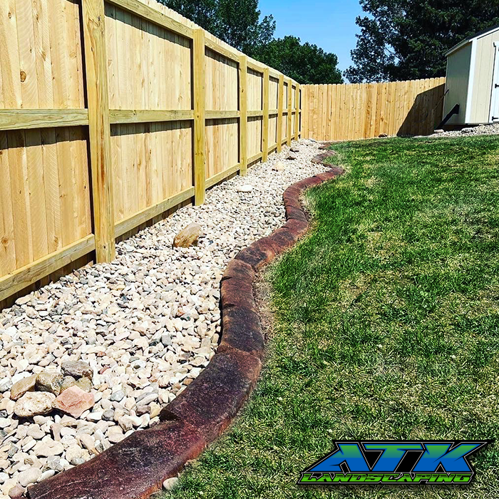 A wooden fence surrounds a lush green yard