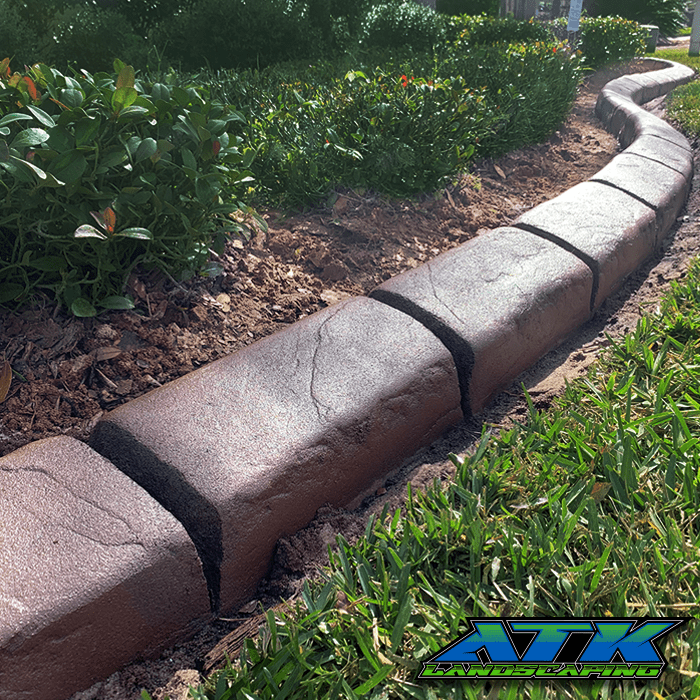 A concrete curb is sitting in the grass next to a garden.