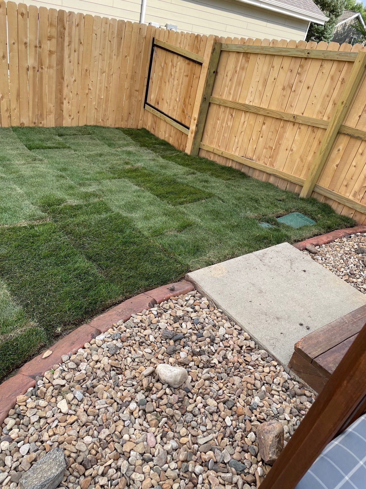 A backyard with a wooden fence and a lush green lawn.