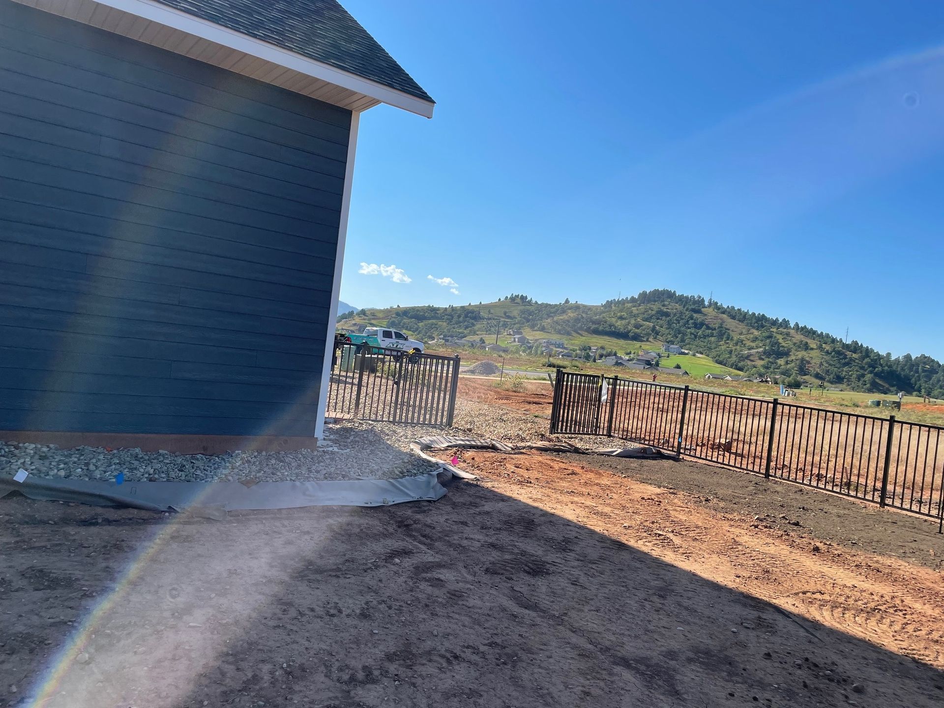 A house is being built on a dirt road next to a wooden fence.