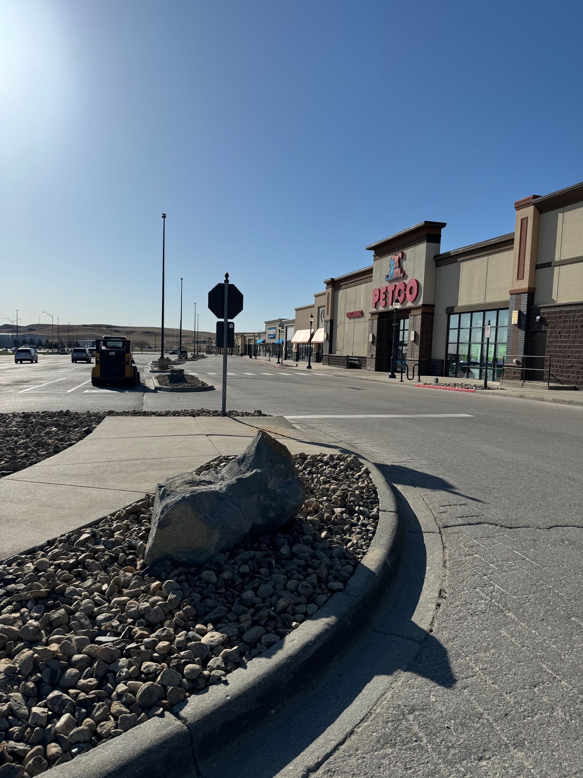 A parking lot with a store in the background and a large rock in the foreground.