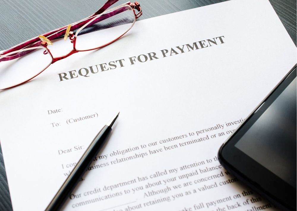 Payment request document beside glasses and phone, warning renters to confirm demands before transferring funds.