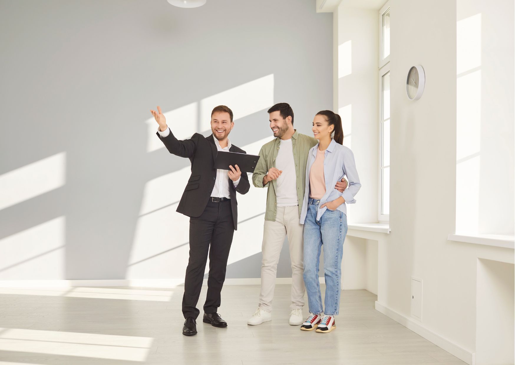  Agent in suit showing modern room to couple, bright interior with large windows.