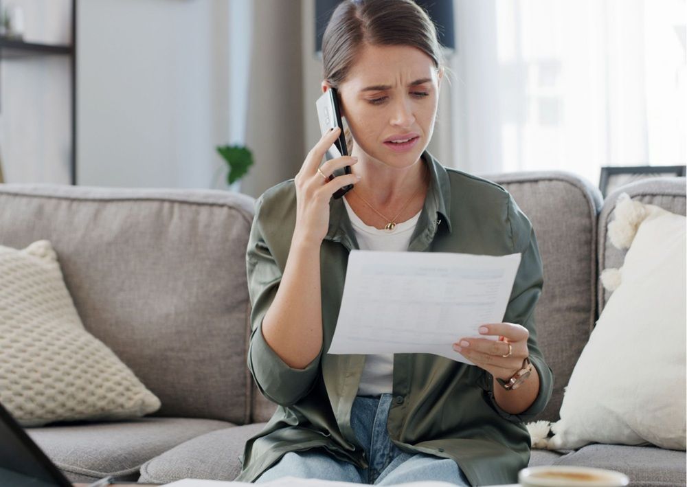 Concerned woman reviewing a rental document during a phone call, highlighting possible scam warning signs.