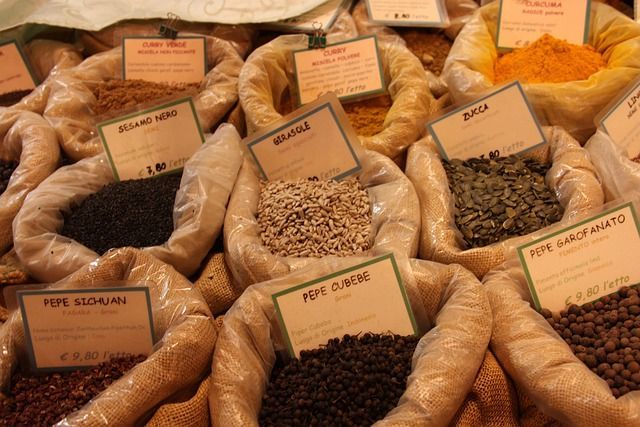 Bags of various spices on display at a market, with labeled tags.