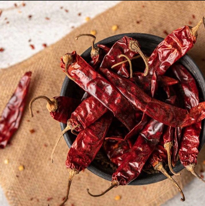 Dried red chilies piled in a white bowl.